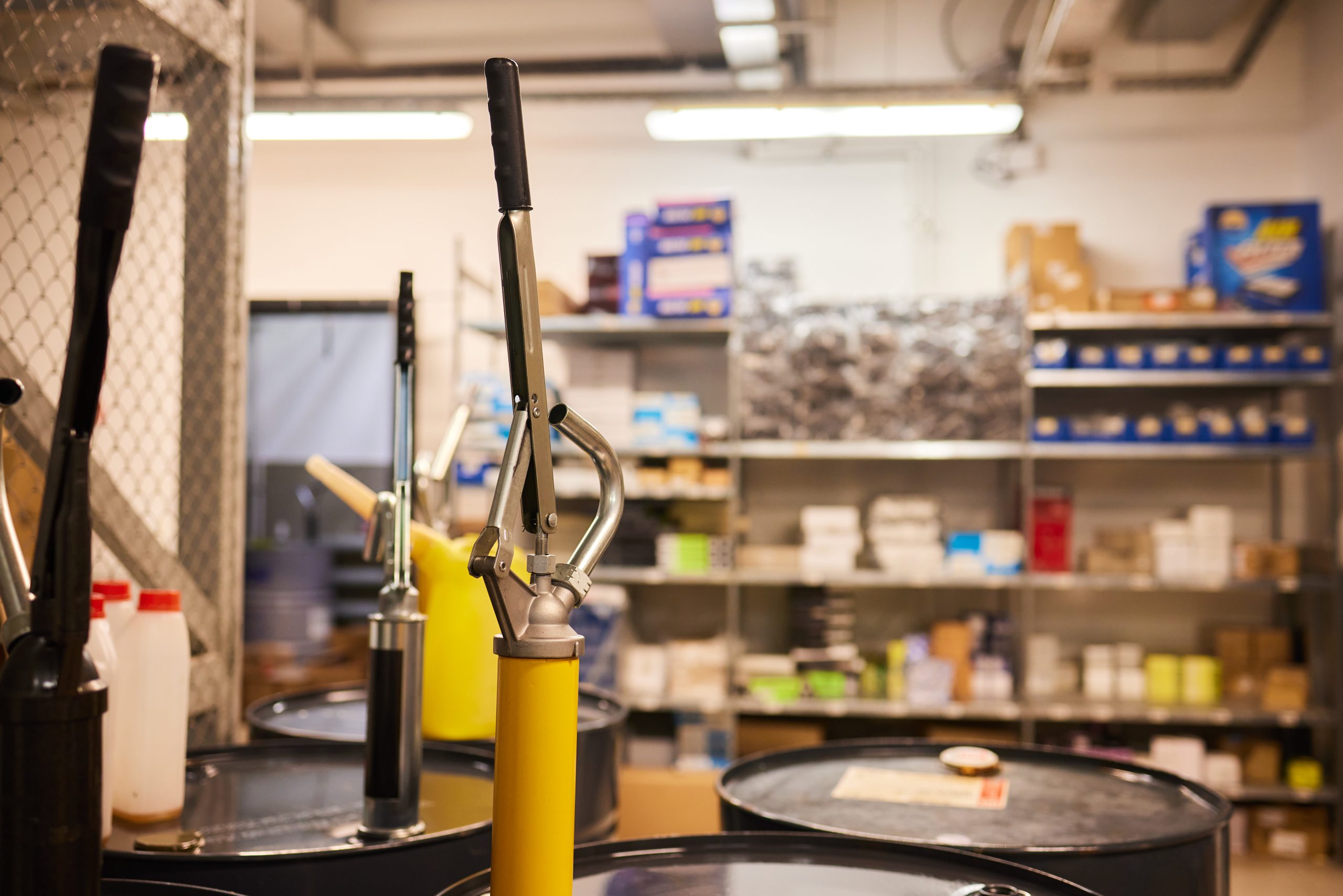 Motor oil in barrels with pump indoors with copy space. Store of lube. Product for bottling close up. Maintenance. Warehouse inside. Background of automotive shop. Auto service. Change of oil.